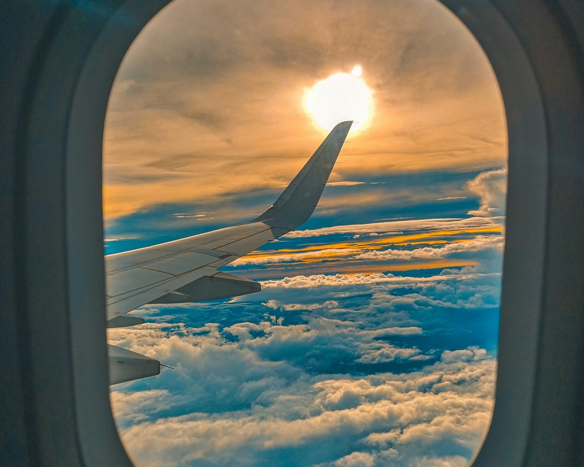 An aeroplane wing above the clouds at sunset