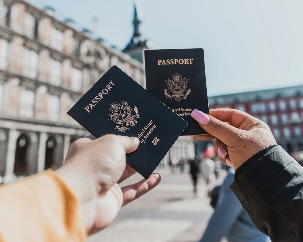 Two passports held up in a city square